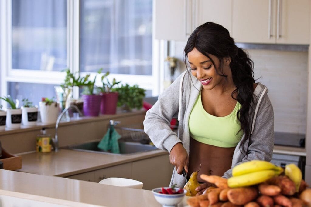 A woman in sportswear preparing food in a kitchen.