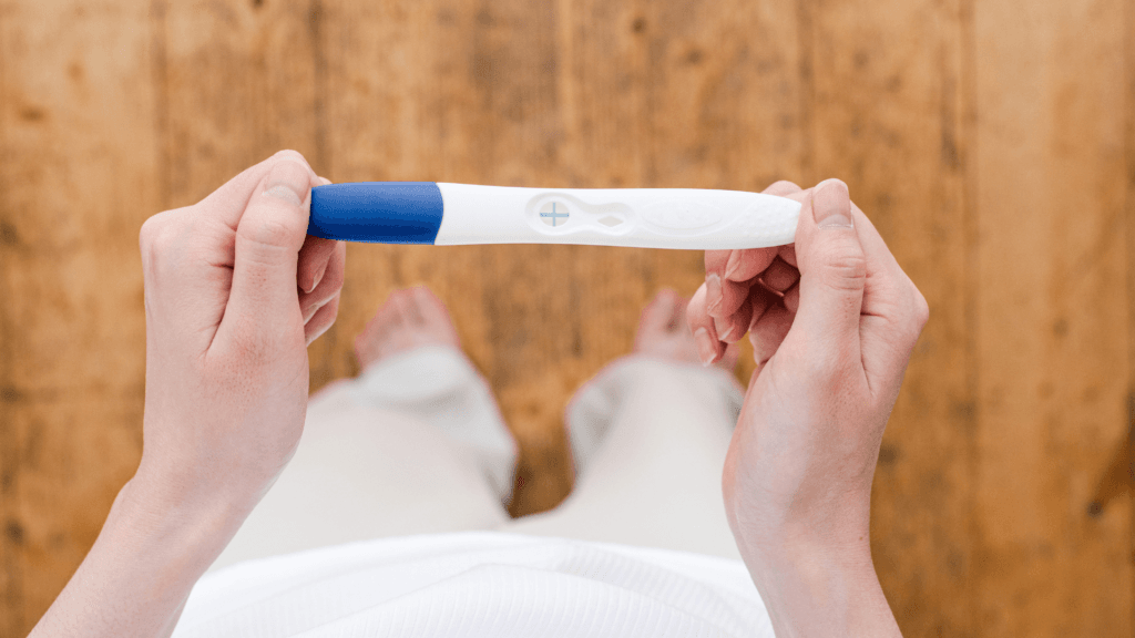 A person holding a positive pregnancy test.