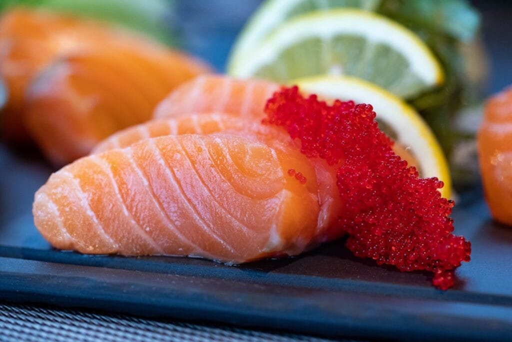 A plate of salmon sashimi topped with red caviar.