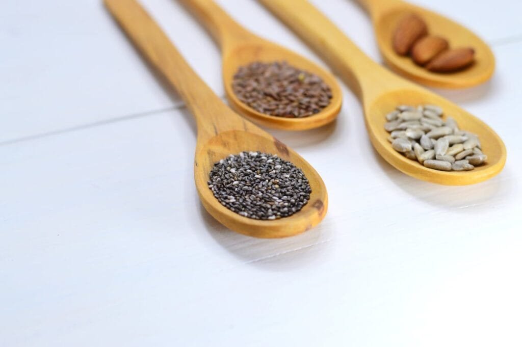 Different types of seeds in wooden spoons. One of these seeds is chia seeds.