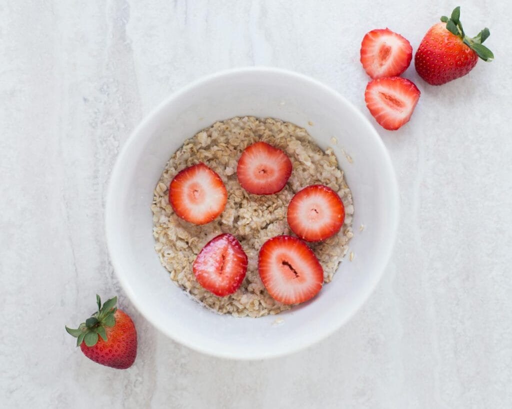 A bowl of oatmeal topped with sliced strawberries.